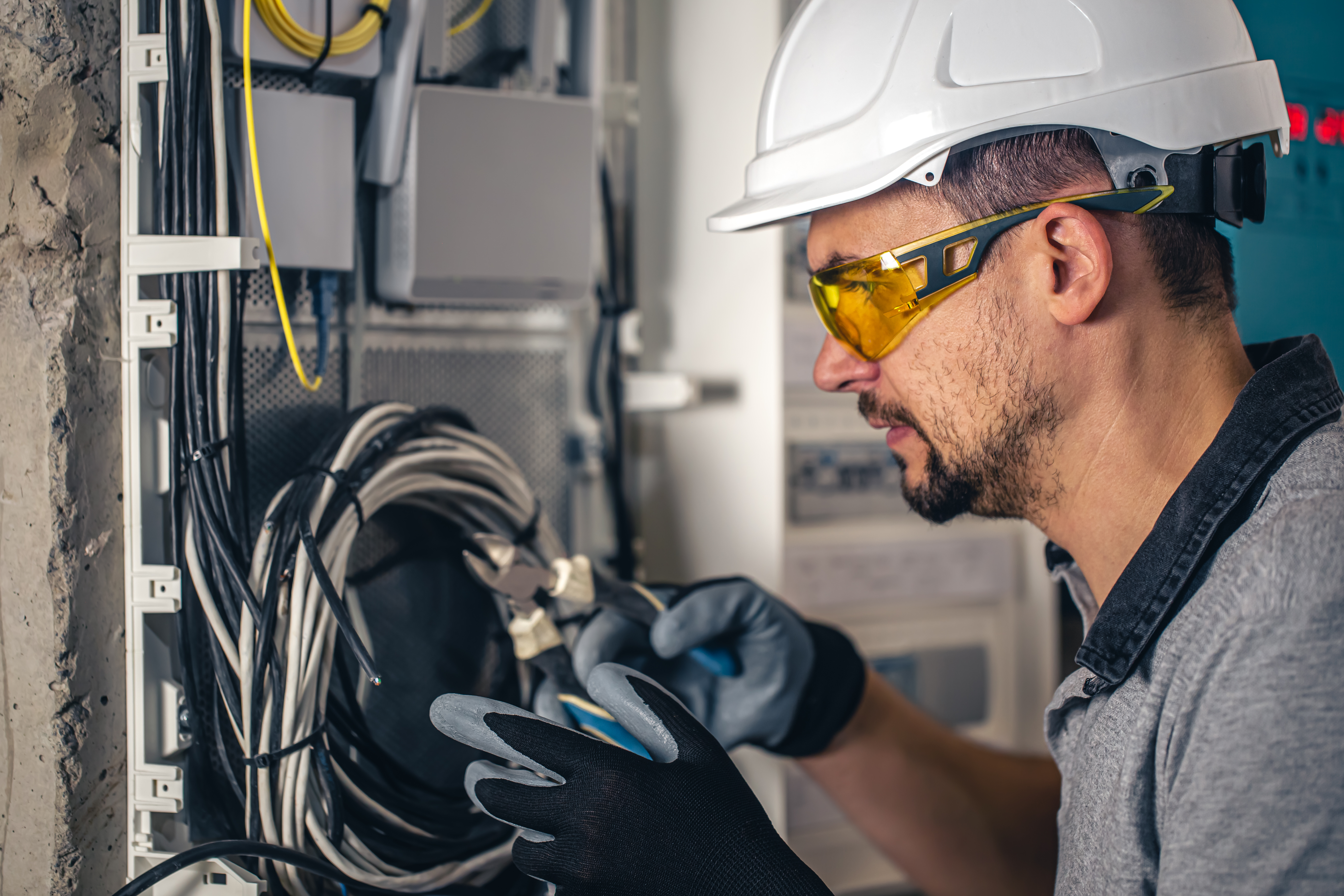 Electrician working at an open switchboard, verifying circuits with a test instrument